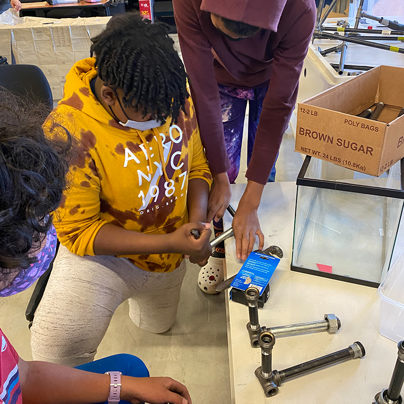 Three students working to assemble parts of an aquaponics tank.