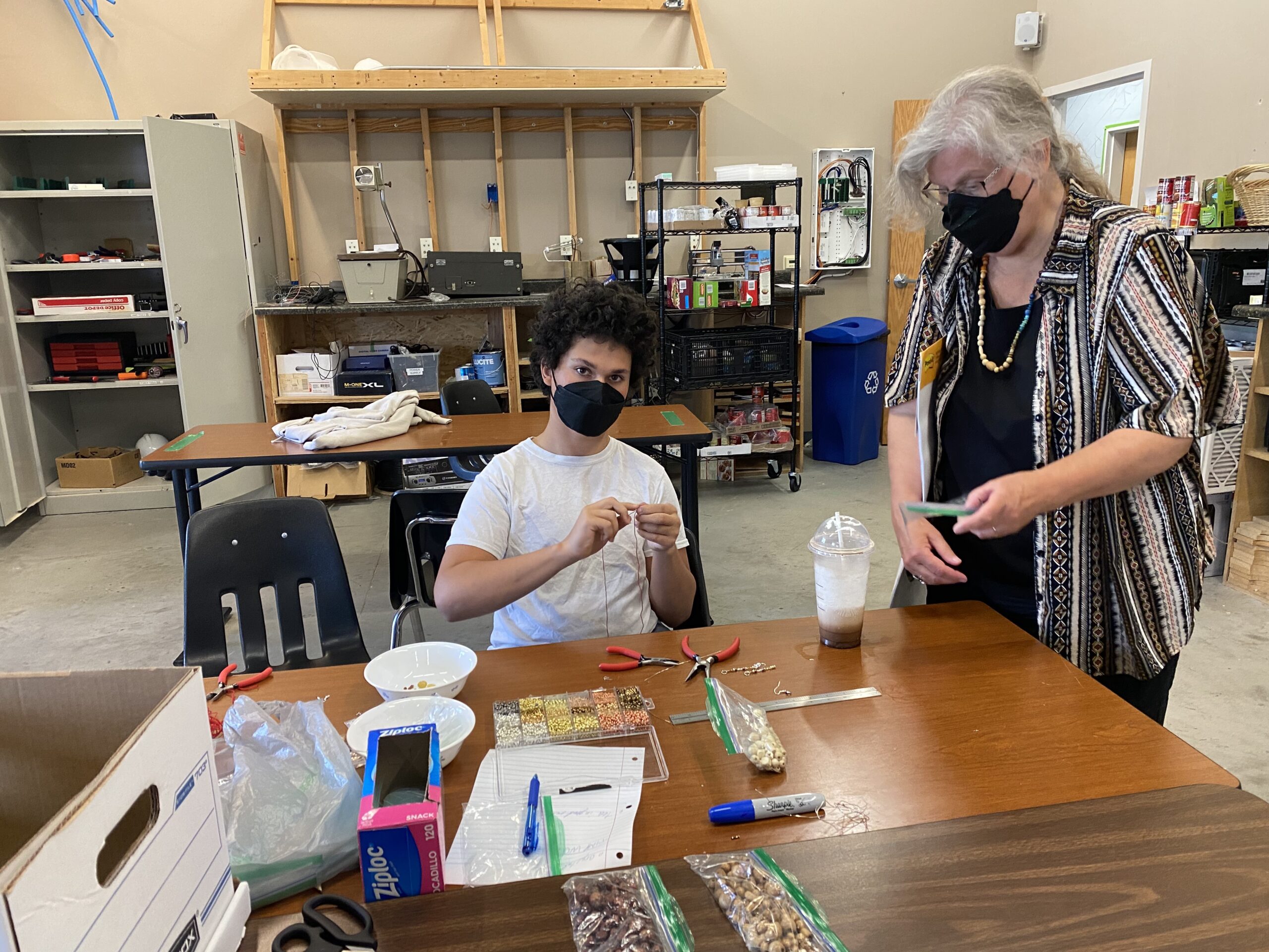 Instructor working with student on beadwork at Milestone.