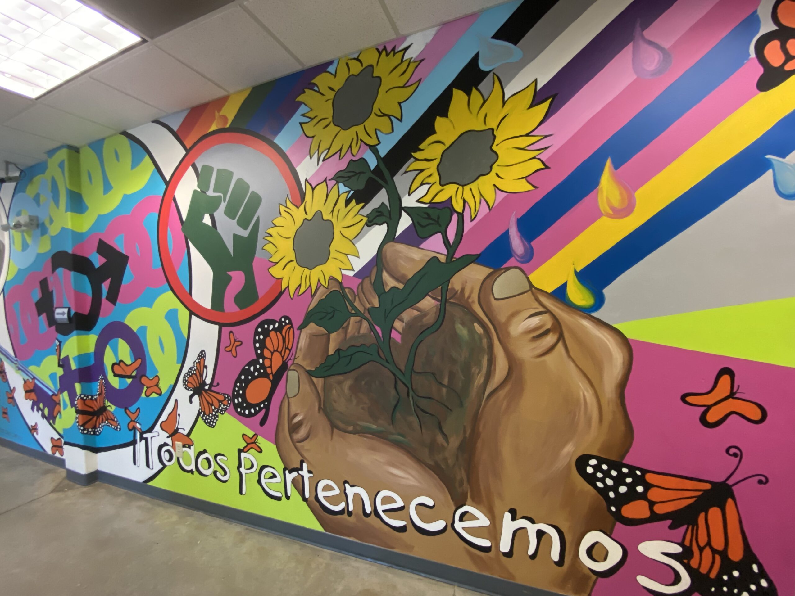 Detail of school mural showing two hands with sunflowers growing and bright background.